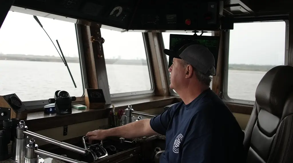 A Southern Devall Barge captain manning the helm of a tow boat